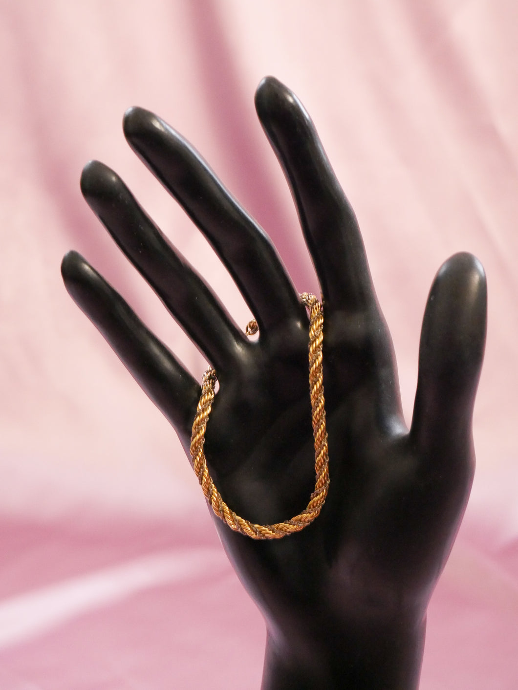 vintage 1980's gold rope bracelet hanging off of  black mannequin hand