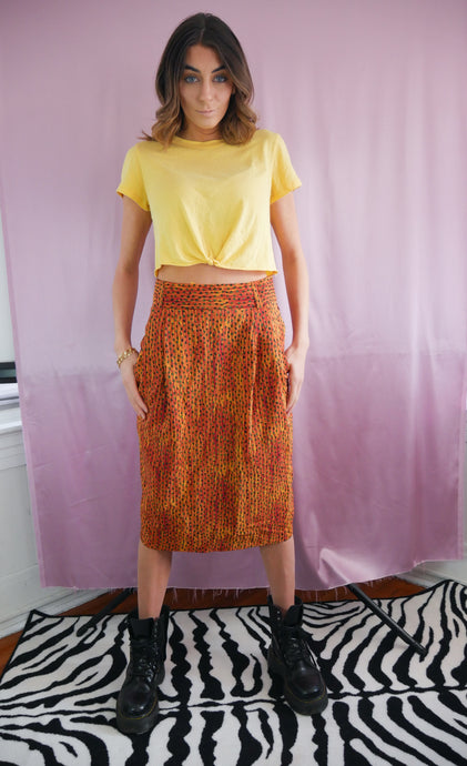 woman wearing a vintage 1980's orange and green silk high waisted skirt, doc martens and yellow tshirt. women's clothing
