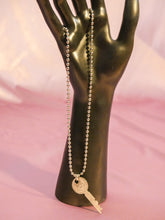 Load image into Gallery viewer, hand holding a vintage key charm on a silver chain necklace. jewelry
